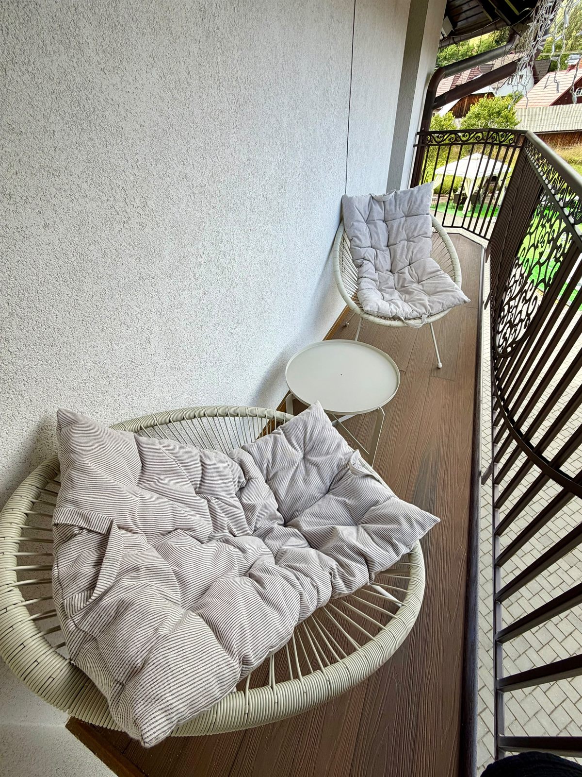Balcon cu două fotolii rotunde, perne și măsuță, cu balustradă din fier forjat