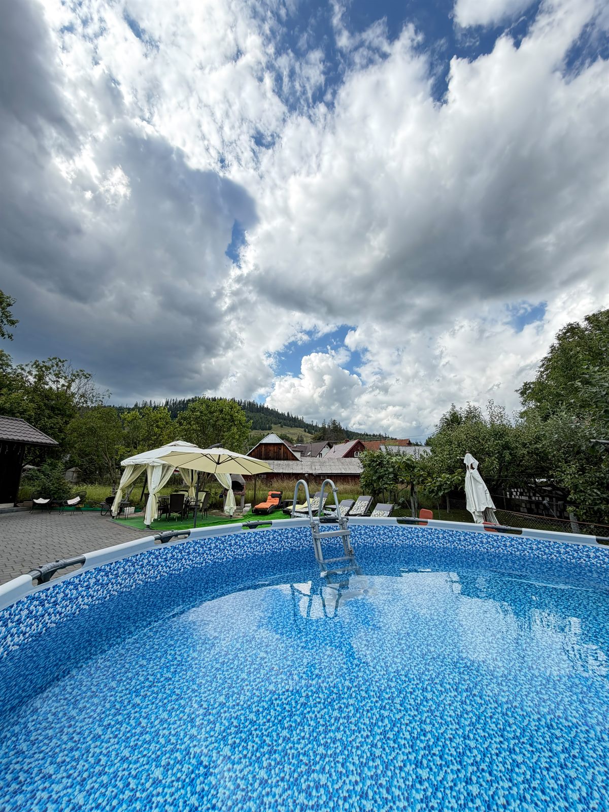 Piscina din grădina Casei Alexandra, cu foișorul și dealurile împădurite ale Bucovinei în fundal